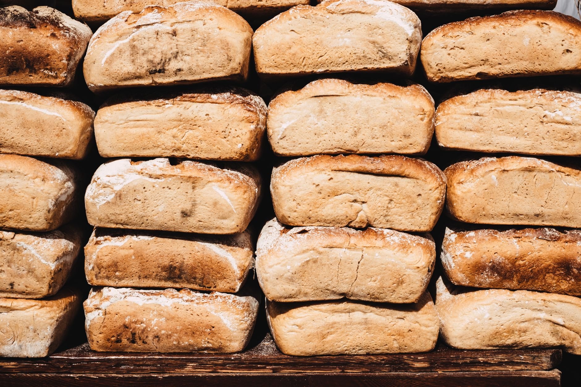 A stack of freshly baked rustic bread loaves on a wooden board.
